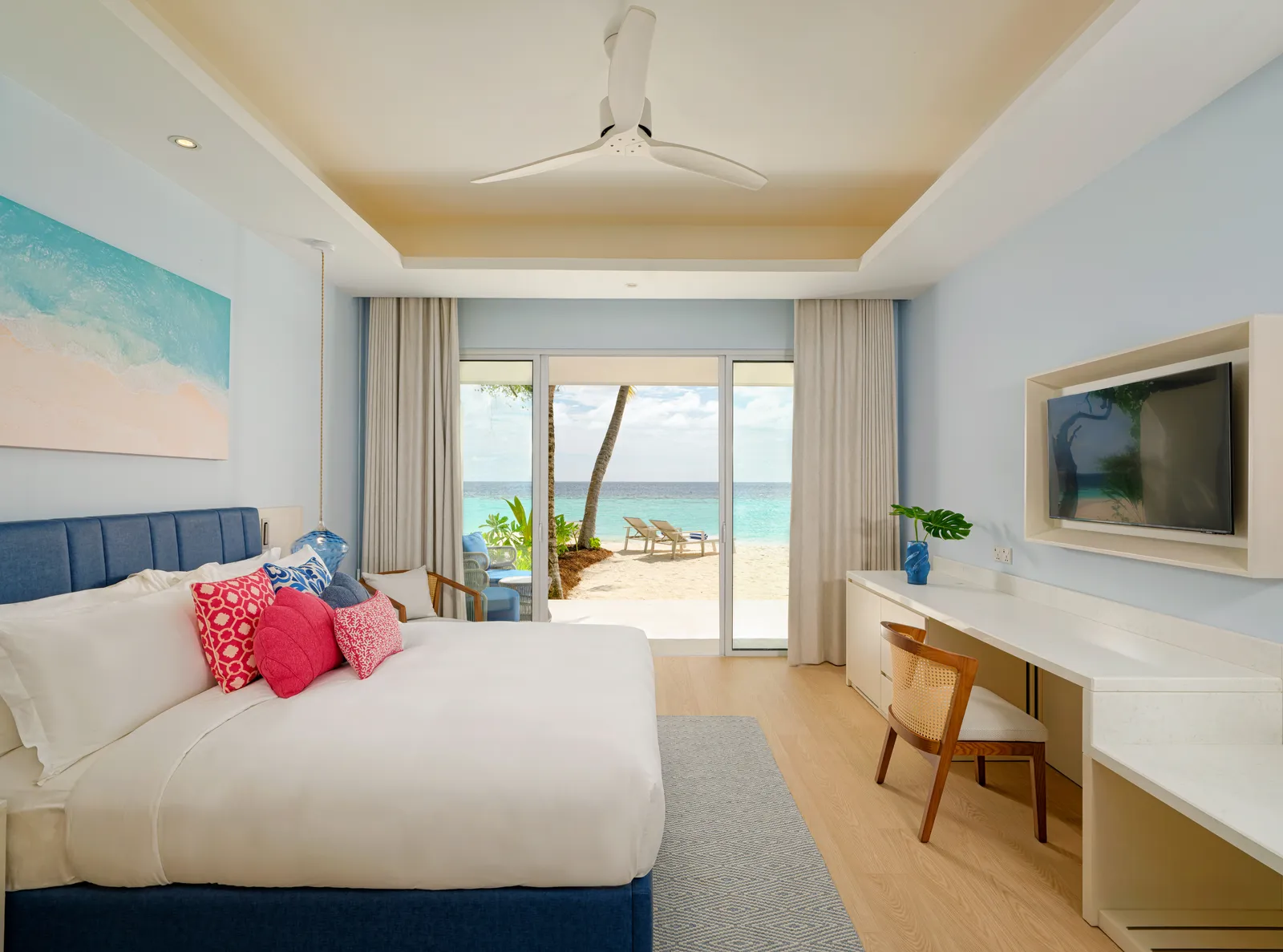A Sunset Beach Villa bedroom: the king bed, a beach painting and the glass doors open onto the sand.