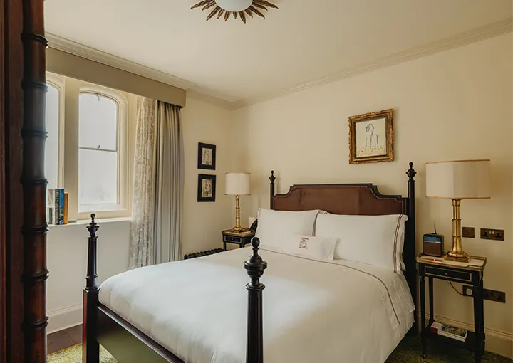 A Cosy Room: a dark four-poster, a bedside lamp and a mullioned window