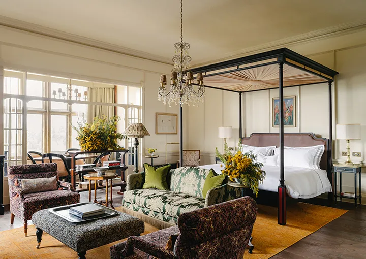 An Estelle Suite: sofa and velvet chairs under a crystal chandelier, the four-poster alongside