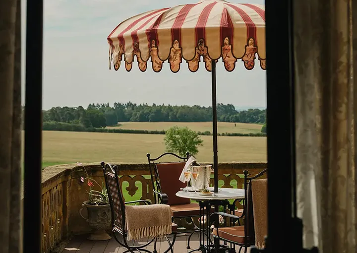 An Estelle Suite’s private balcony, a striped umbrella above the fields