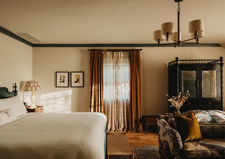 A Large Walled Garden Room: the bed, a lacquered cabinet and rust-coloured curtains