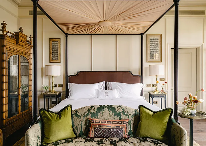 A Manor House Suite: a four-poster with a pleated canopy and a green sofa