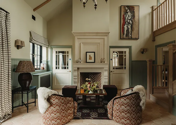 The Farriers: the double-height living room with a stone fireplace and armchairs