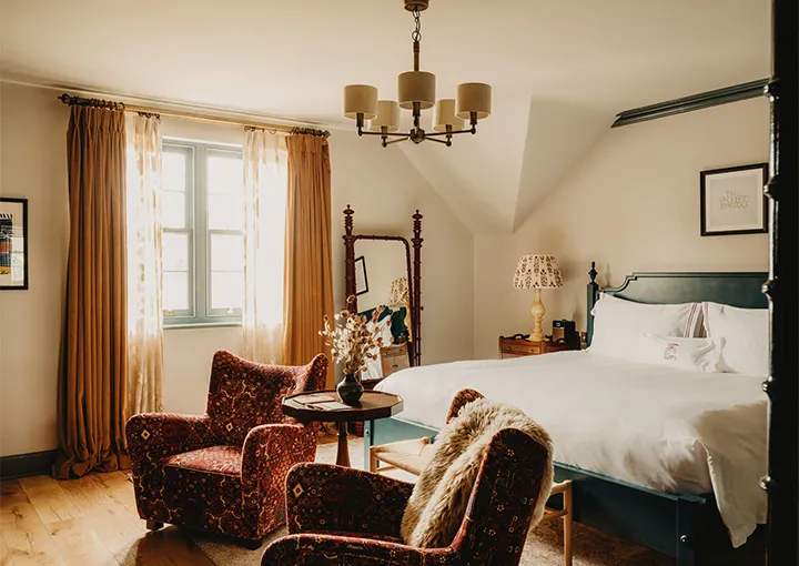 A Walled Garden Room: red velvet armchairs and the bed under the chandelier
