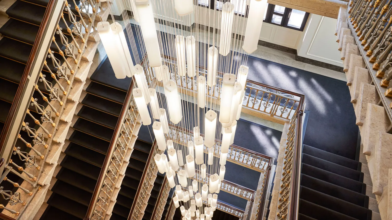The period staircase seen from above, with the cascade chandelier falling through the stairwell
