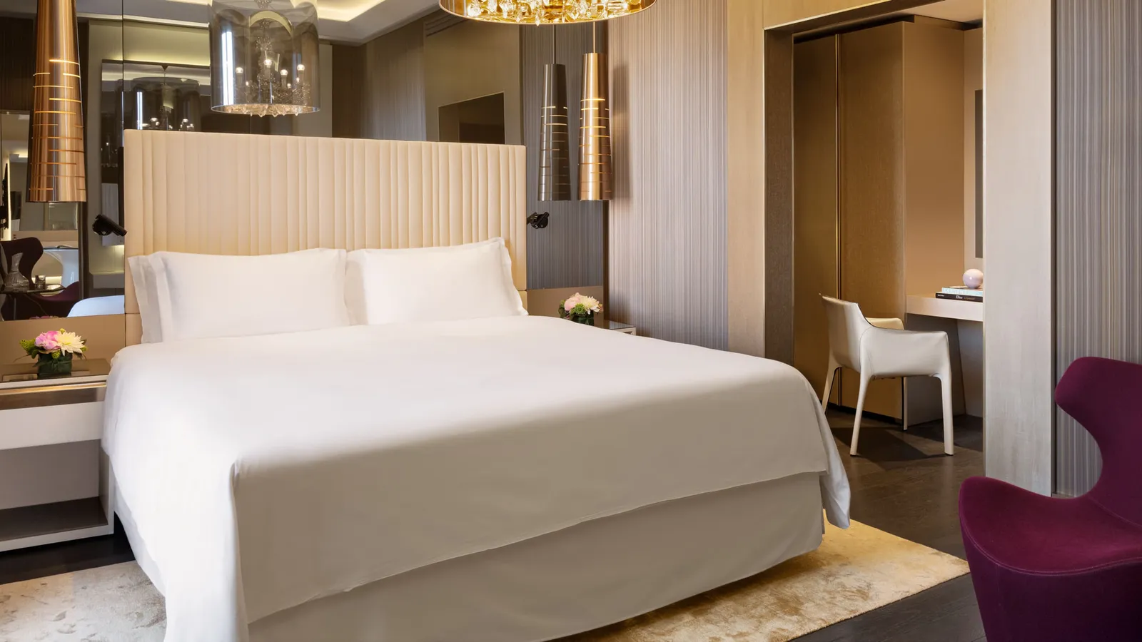 The bedroom of a Signature Suite, with a purple armchair