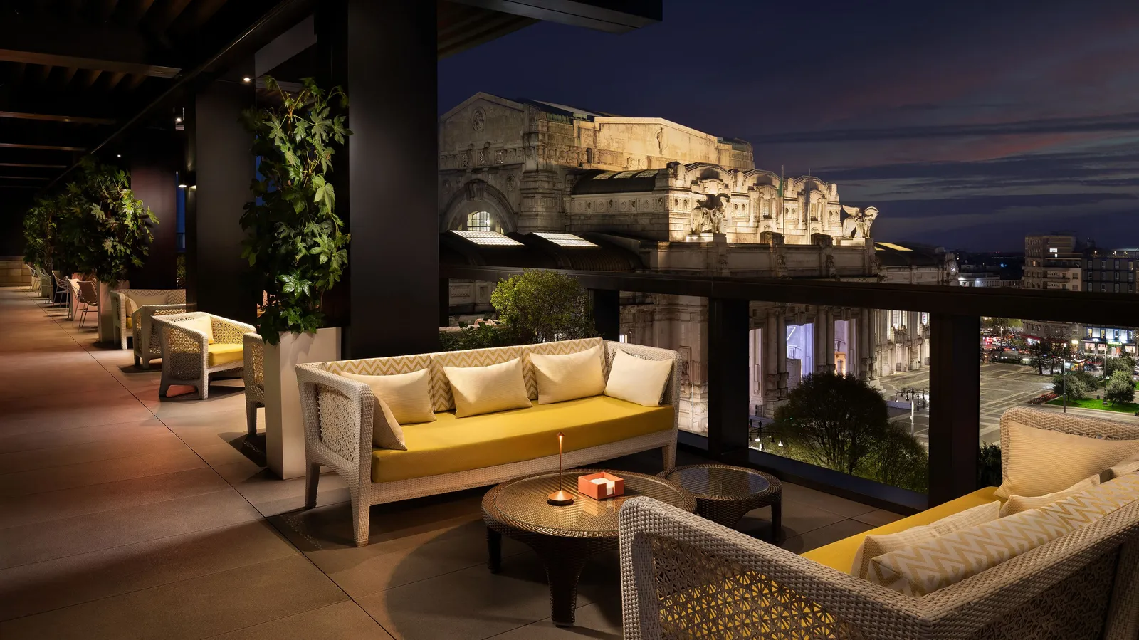 Terrazza Gallia at dusk, lit sofas in front and Milano Centrale lit up behind