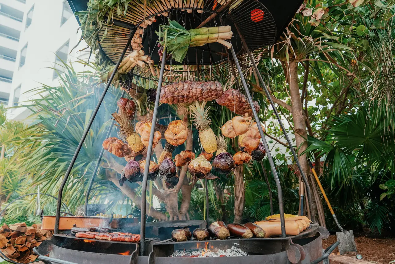 The iron asado dome in the garden: pineapples, vegetables and cuts of meat hanging above the fire.
