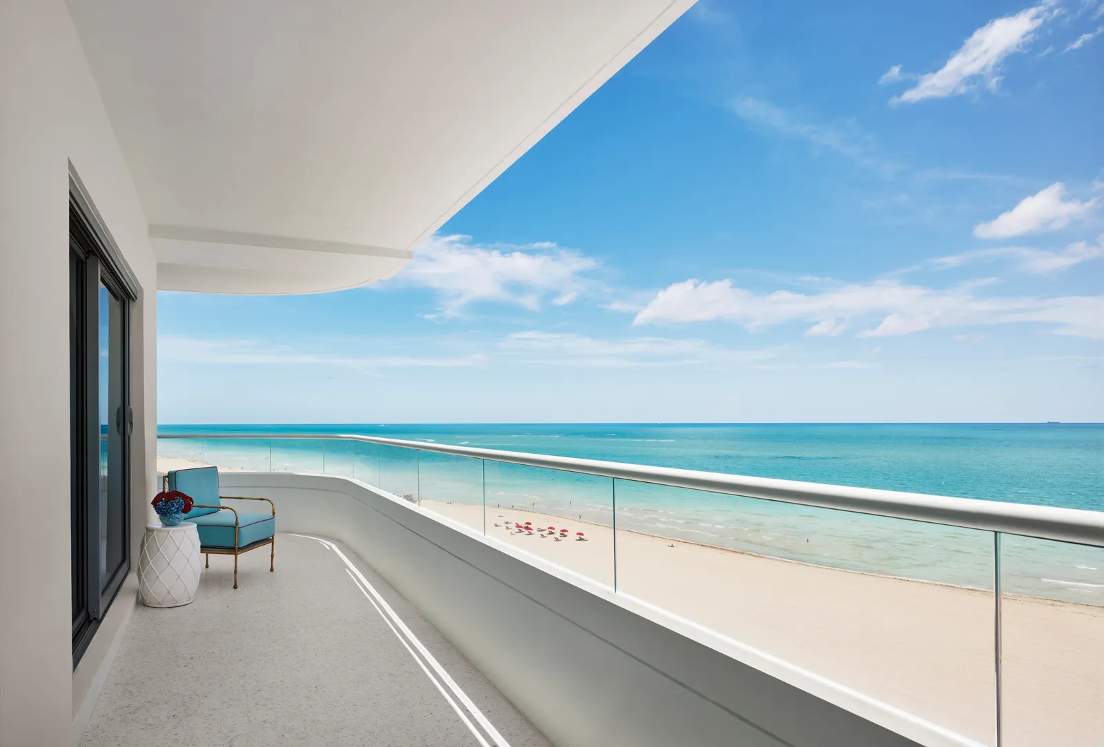 A curved balcony with a glass balustrade above the beach and the ocean.