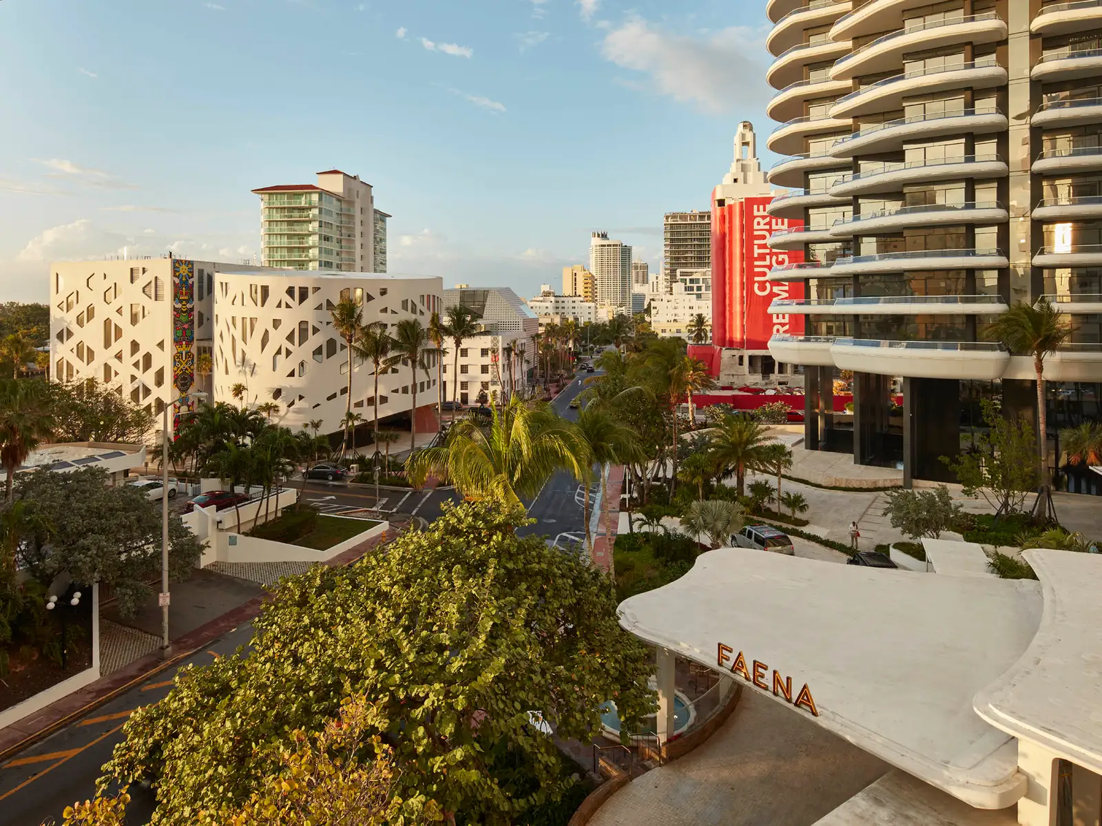 Collins Avenue from above: the white cut-out façade of the Faena Forum on the left, palms and, in the foreground, the canopy with the Faena name.
