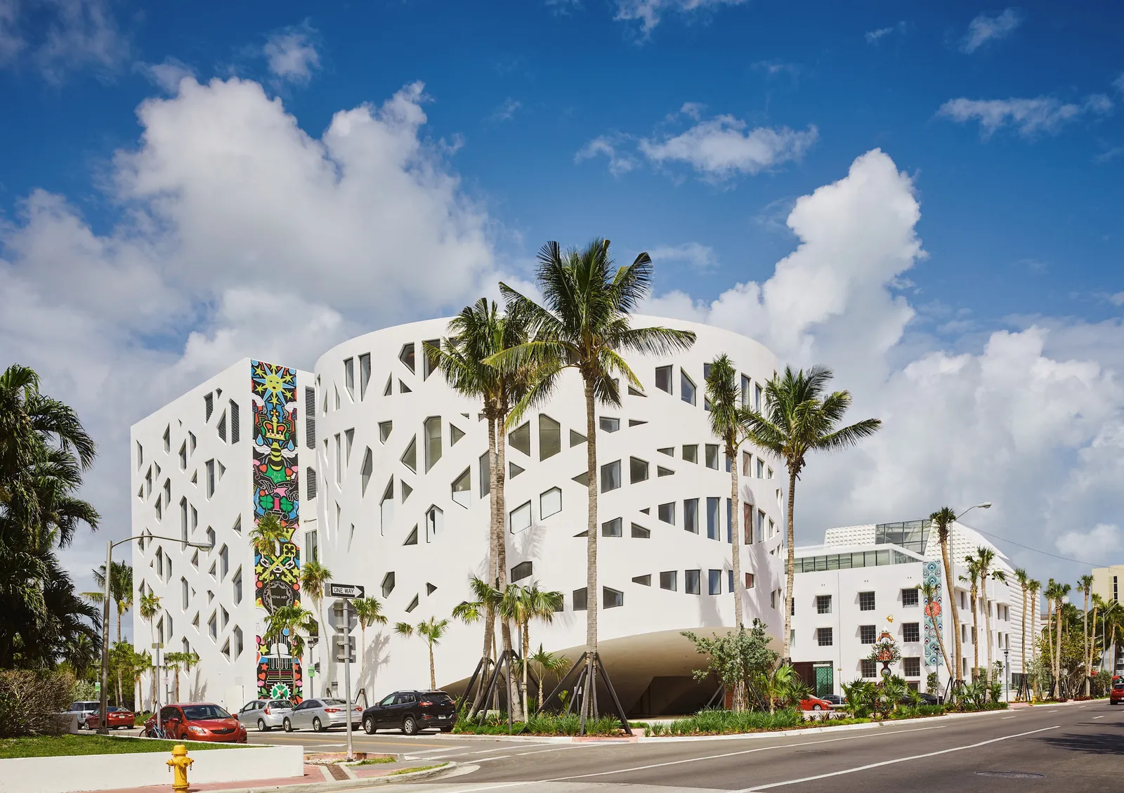 The Faena Forum from Collins Avenue: a white building with a cut-out façade, among palms.