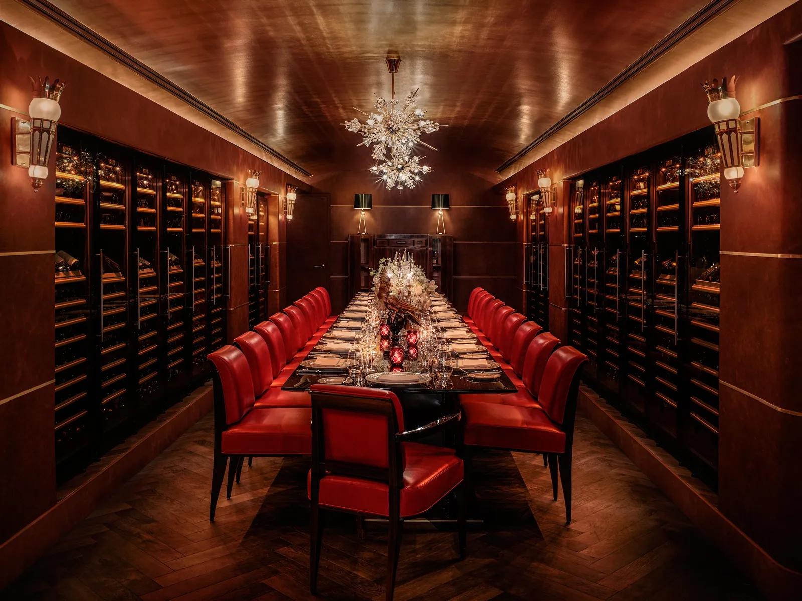 La Cava: a long laid table with red leather chairs between 2 walls of bottles.