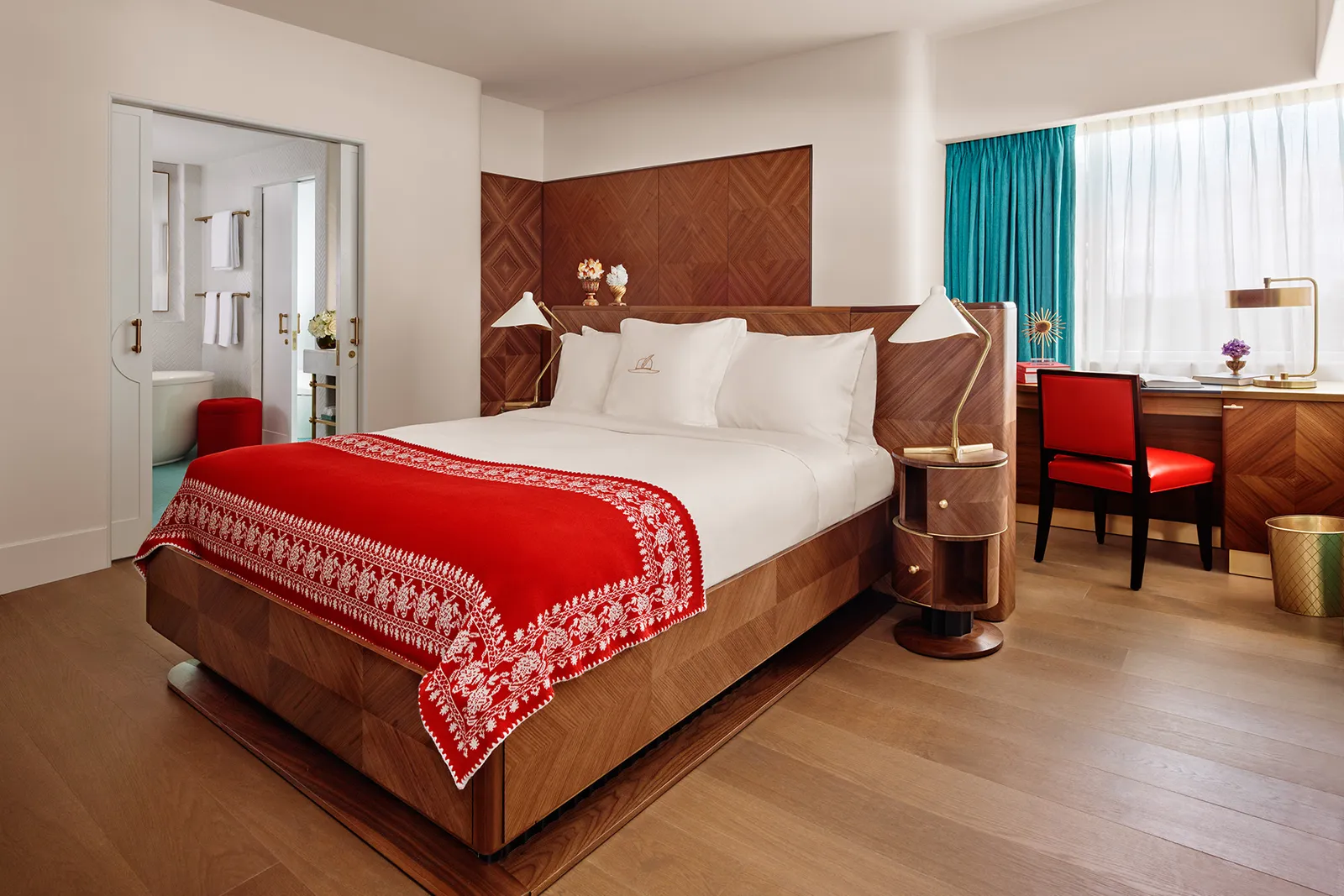 The Bay View Queen Junior Suite: the bed with its wooden headboard, the desk with a red chair and a turquoise curtain.
