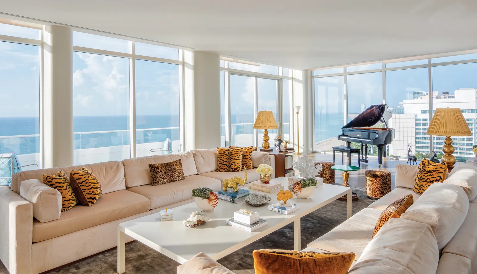 The Faena Penthouse Suite’s living room: white sofas with tiger-print cushions, the grand piano and windows onto the ocean.