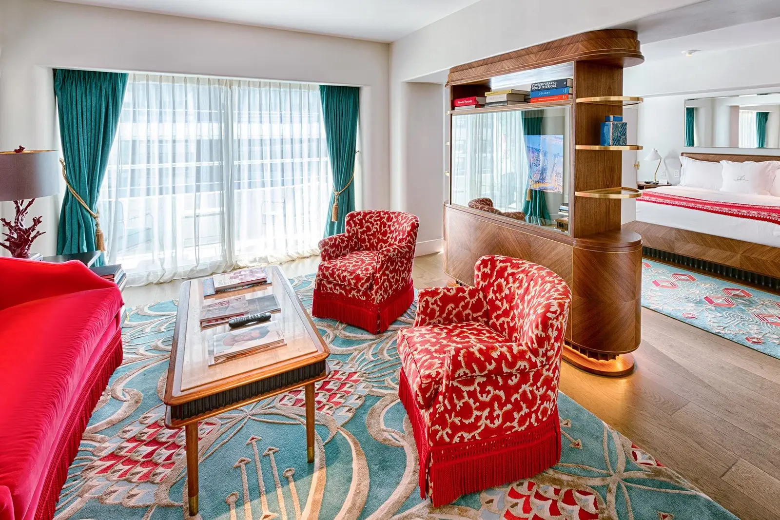 The Partial Ocean View Junior Suite: flowered red armchairs on a turquoise carpet and the bed beyond the wooden divider.