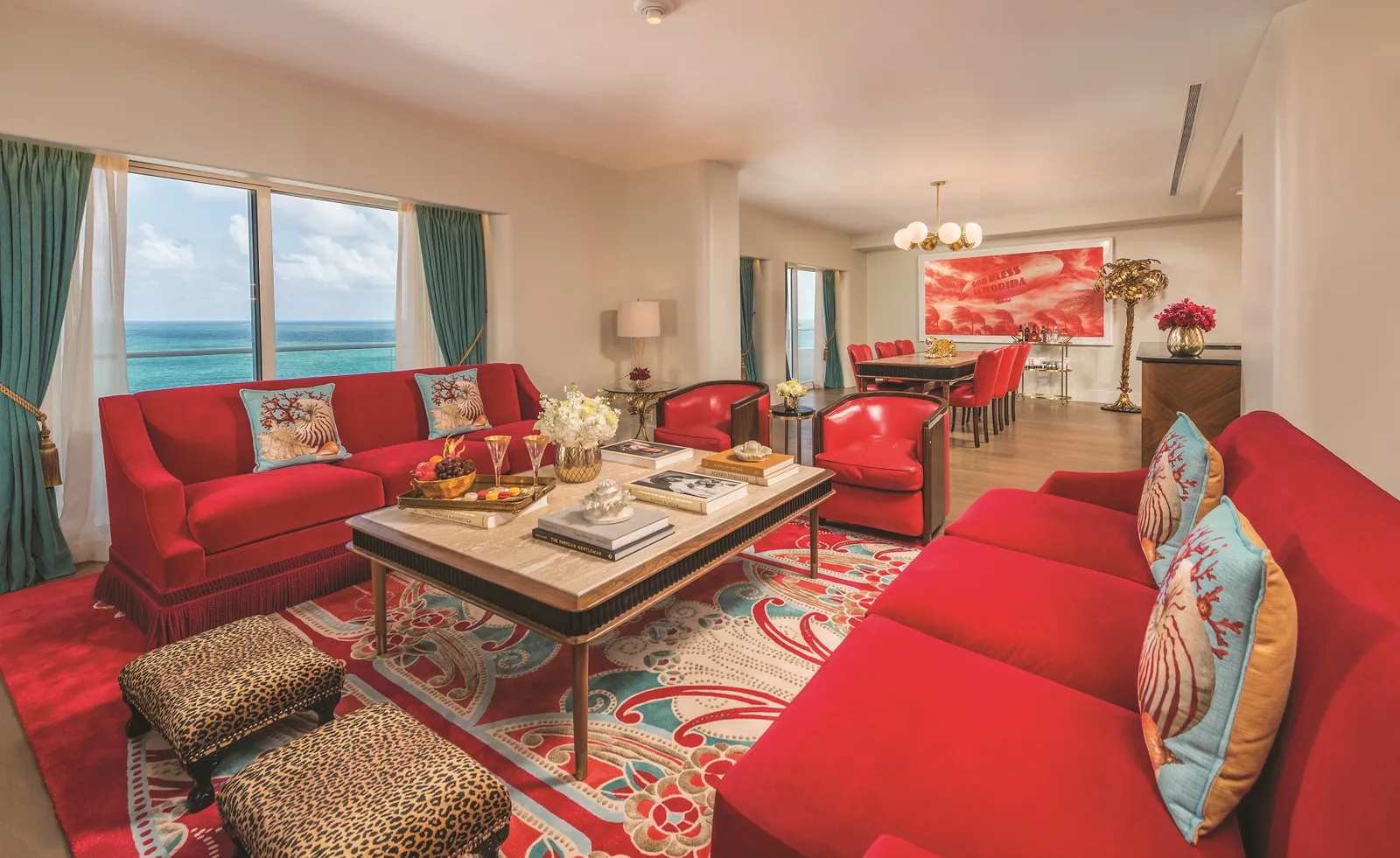 The Premier Oceanfront Three Bedroom Suite’s living room: red sofas, leopard-print stools and the coffee table.