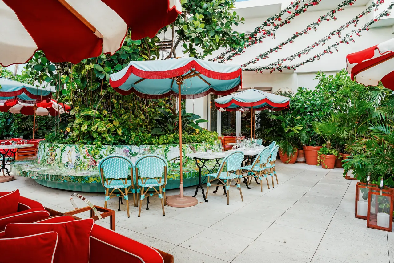 The Tree of Life terrace: bistro tables and chairs around a tree, under red and turquoise parasols.