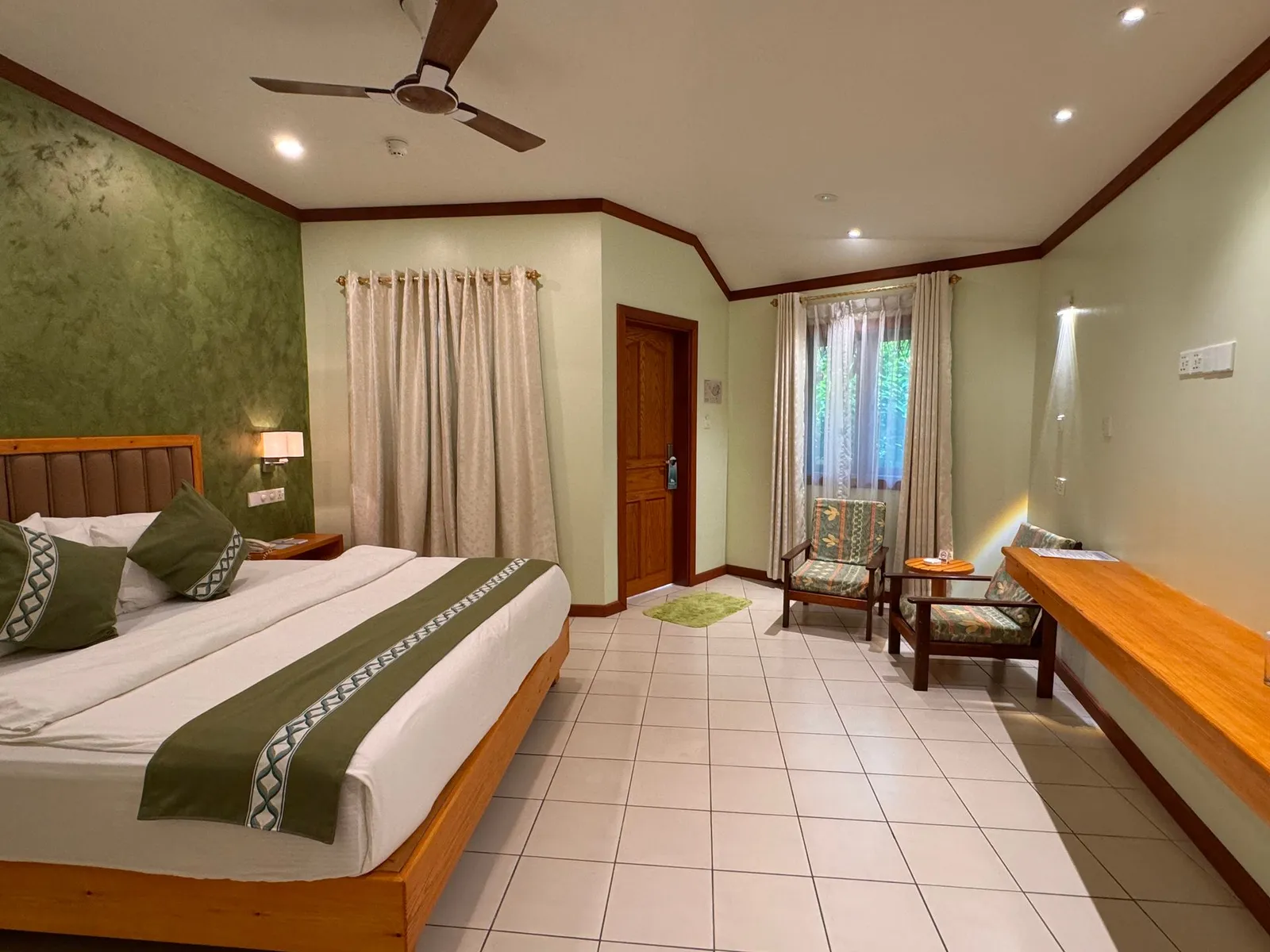 A Deluxe Superior: the king bed, the green wall, the small sitting area by the window and the timber door.