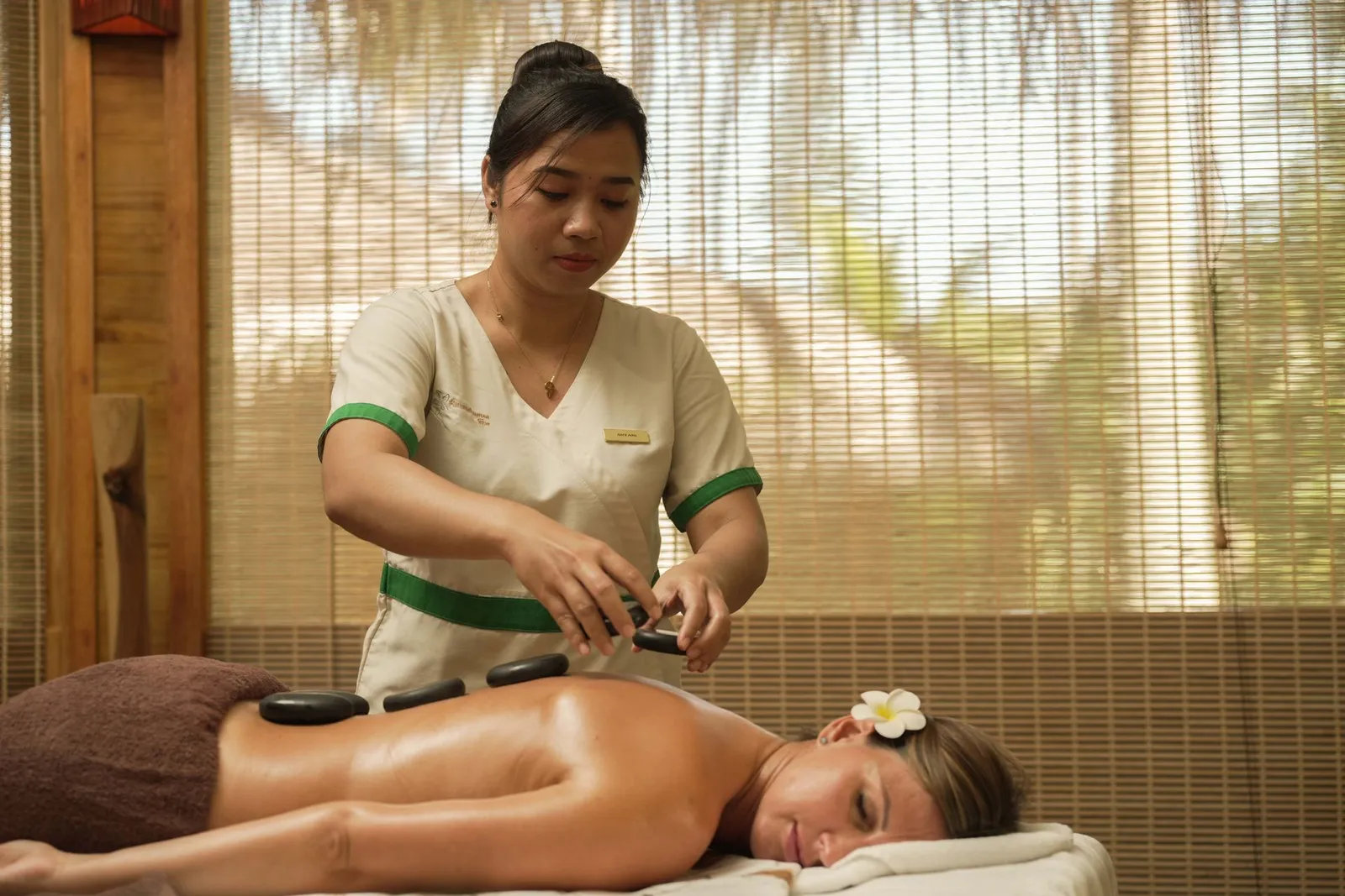 A hot-stone massage in a spa room, the bamboo blind behind.