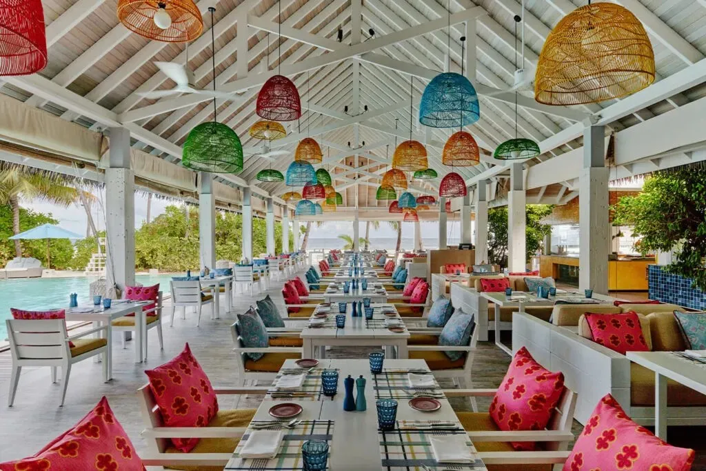 The Beach Kitchen dining room, with colourful wicker lamps and red cushions
