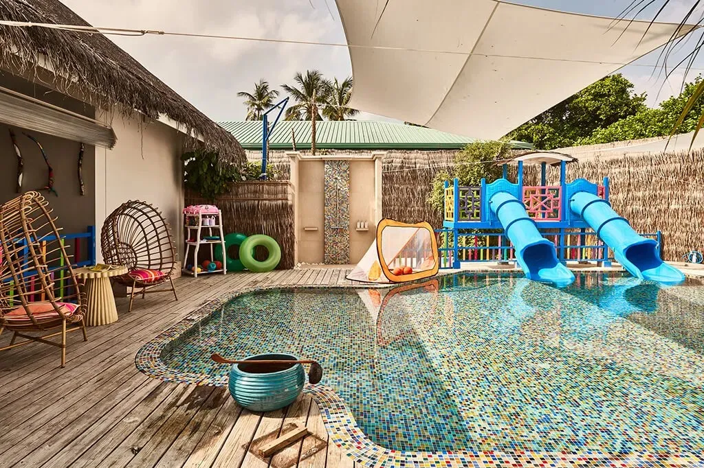 The kids’ club pool with its blue slides, hanging chairs and white shade sail