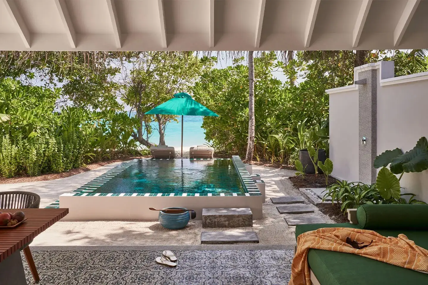 A Beach Pool Villa’s pool in the garden, an umbrella and the beach beyond the plants