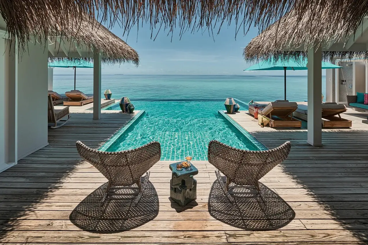 The Two Bedroom Rockstar Villa’s infinity pool, 2 chairs on the deck and the ocean