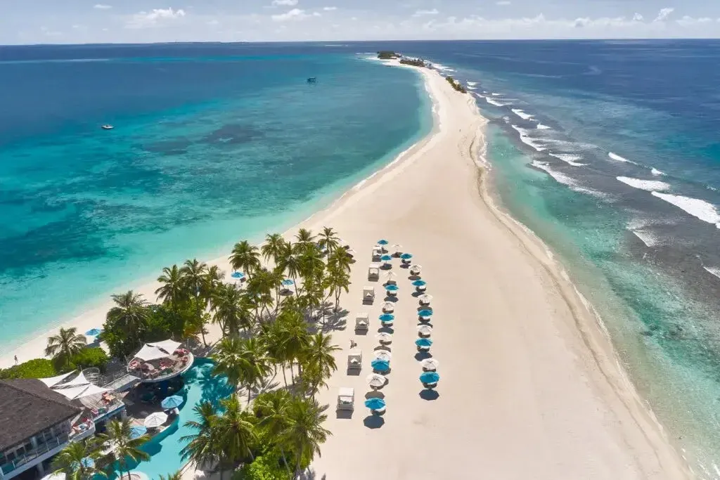 The sandbank running out from the island, with umbrellas, palms and the turquoise lagoon