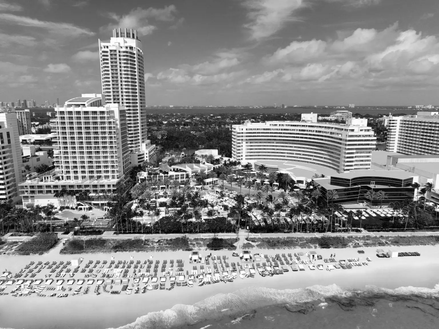 The resort from the air, in black and white: the towers, the curved 1954 building, the pools among the palms and rows of loungers on the beach.