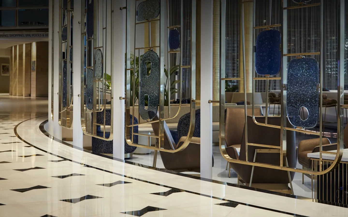 The lobby’s white marble floor with its black bow-tie inlays and, behind a row of white columns, the leather armchairs and the brass and blue-glass screens of Bleau Bar.
