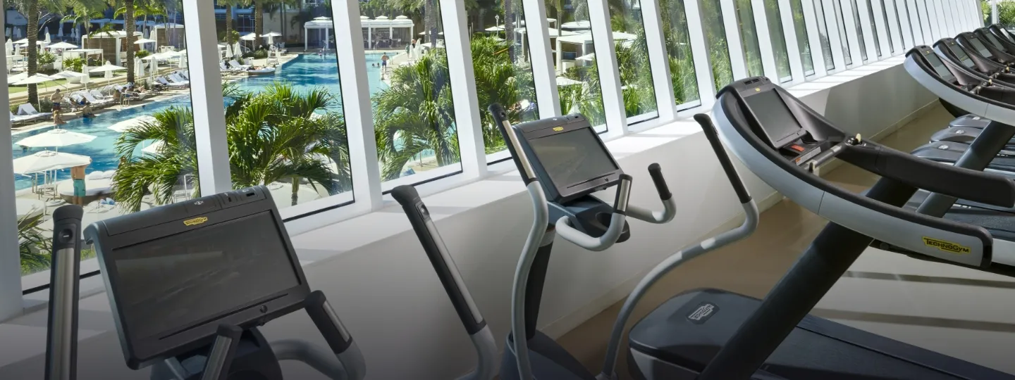 The gym: treadmills and bikes lined up at the windows overlooking the pools.