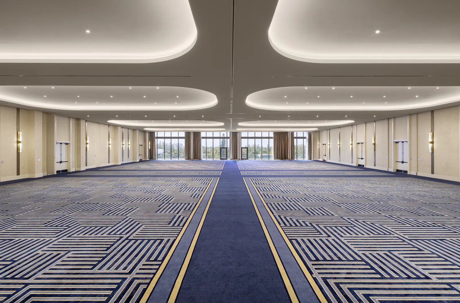 The empty Pearl Ballroom: blue carpet in a geometric pattern, a ceiling of lit curves and windows at the far end.