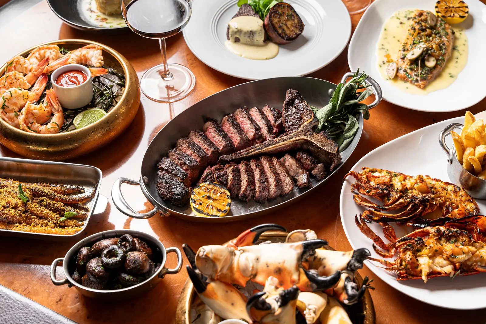 A Prime 54 table from above: a sliced steak in its pan, lobster, crab claws, prawns and side dishes.
