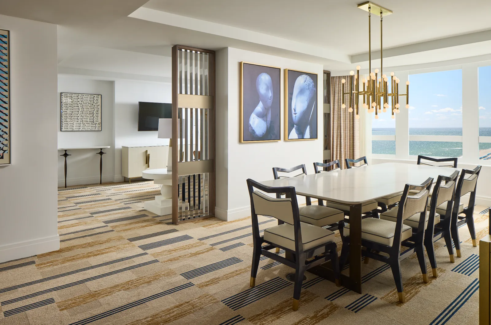 The Grand One Bedroom Suite’s dining area: a table for 8 under a gilt chandelier, a wooden screen and the windows towards the sea.