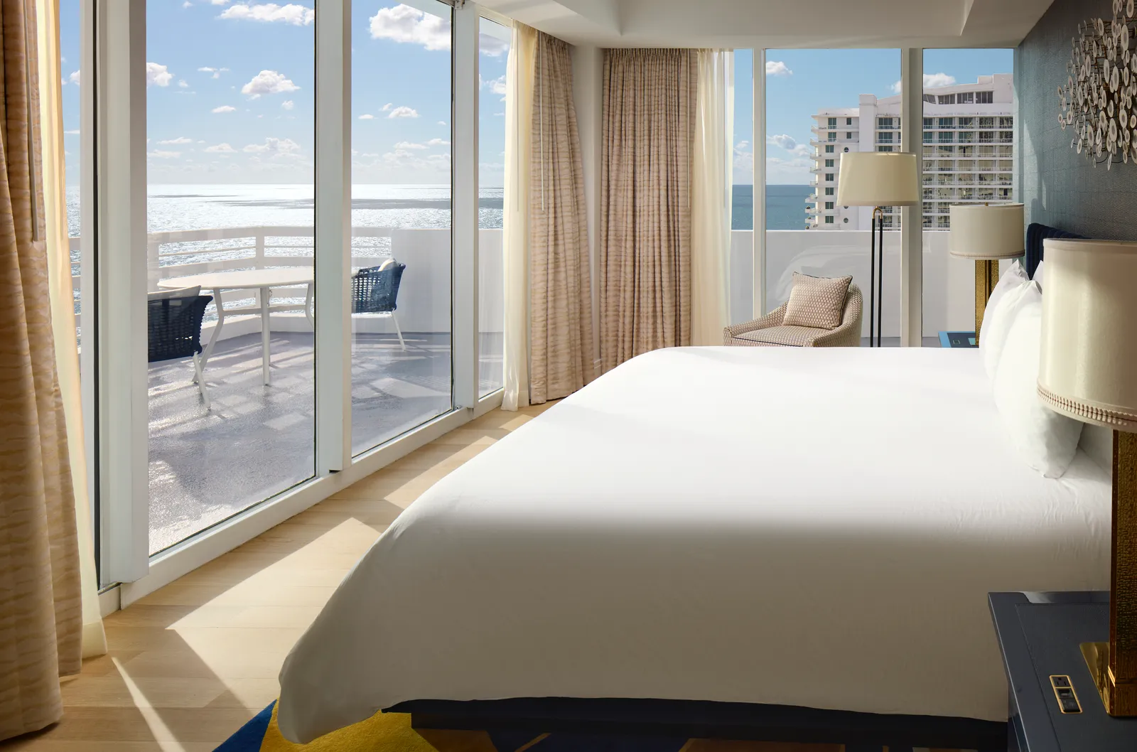 The Le Ciel suite’s bedroom: the white bed facing the glass doors, with the terrace and the hotel’s towers outside.