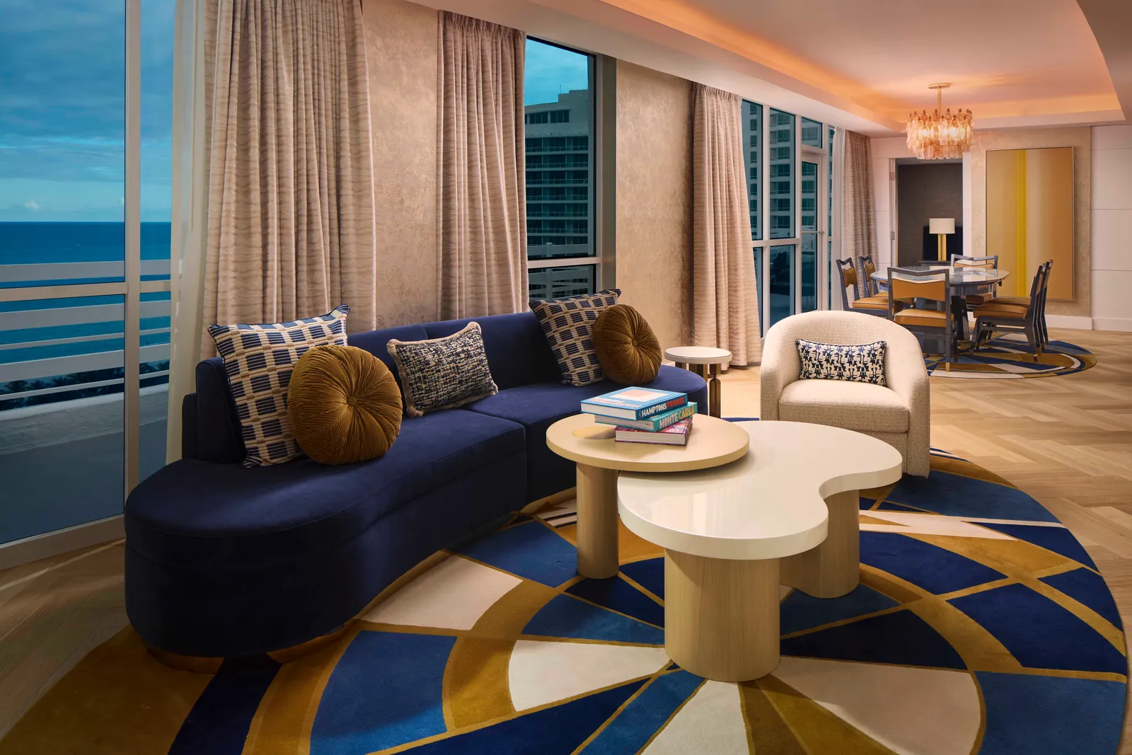 The Le Mer Presidential Suite’s living room: a curved blue sofa, a kidney-shaped table and the window wall onto the ocean.
