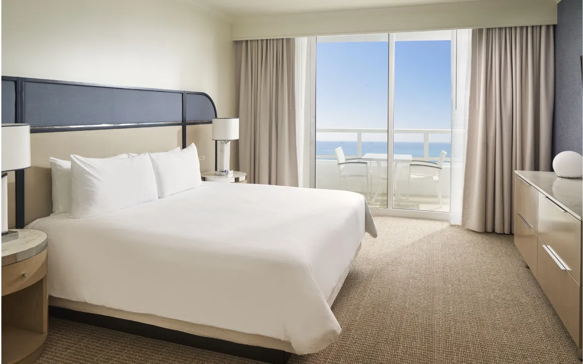 The bedroom of a Trésor Ocean View One Bedroom Suite, with its king bed and the door to the balcony and the sea.