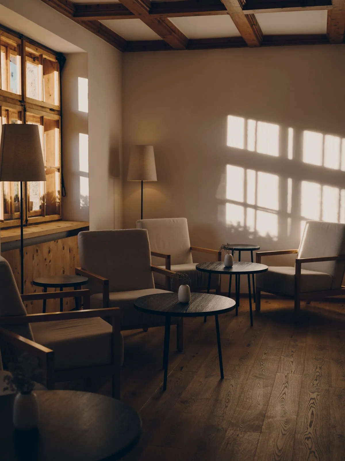 The bar lounge in the historic house: armchairs and round tables on the timber floor, the coffered ceiling and window light on the wall.