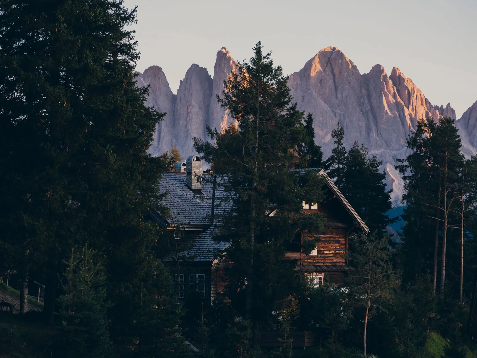The Villa among the firs, with its shingle roof and wooden loggias, below the Odle spires turned pink at sunset.