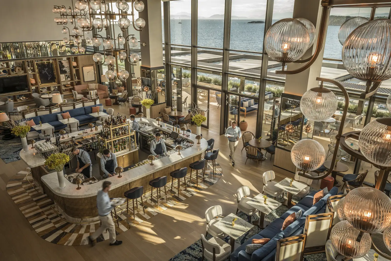 Avra bar from above: the horseshoe counter, blue sofas, glass lanterns and windows onto the sea.