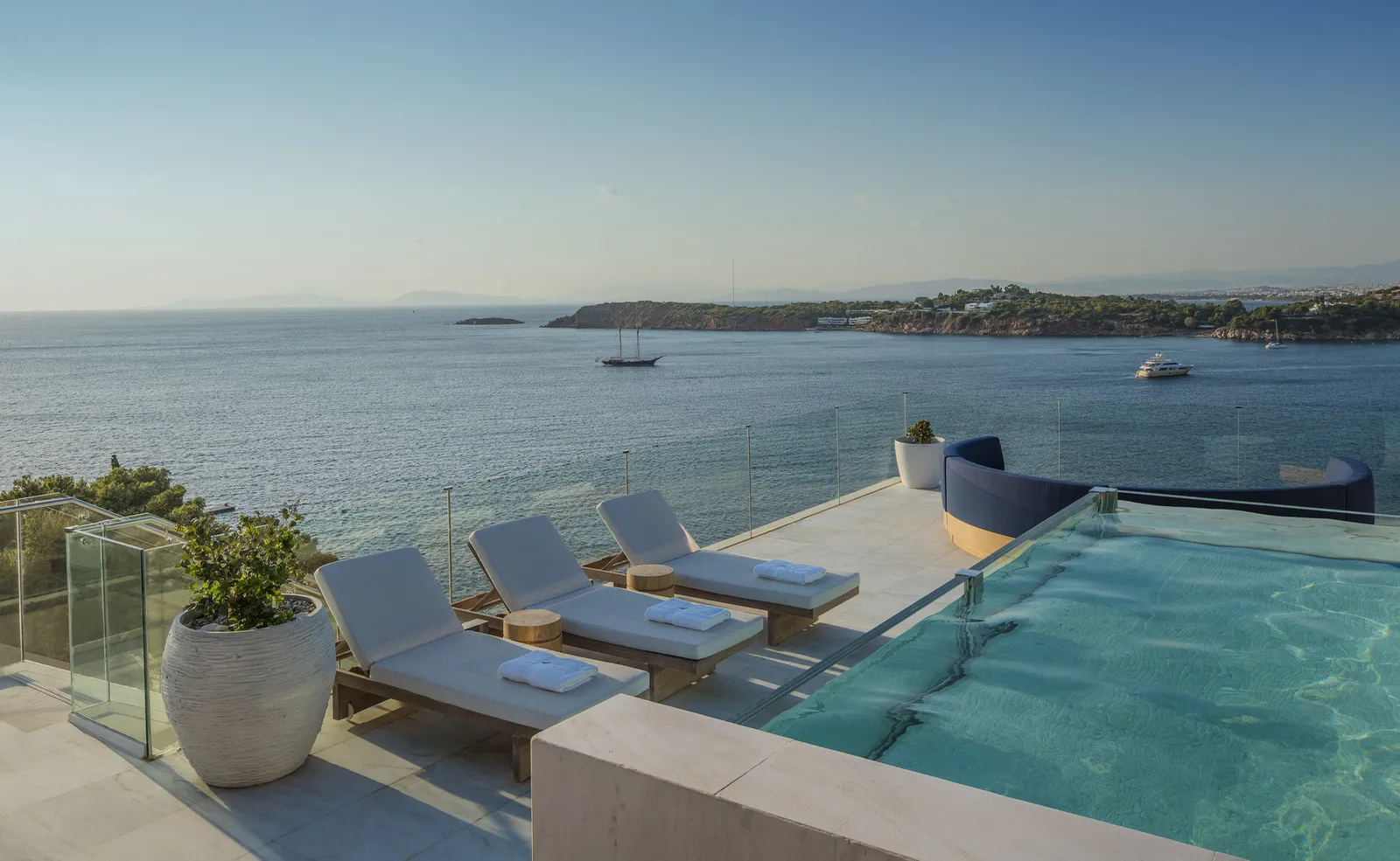 The rooftop terrace of the Arion Presidential Suite: the plunge pool, 3 loungers and the bay with boats at anchor.