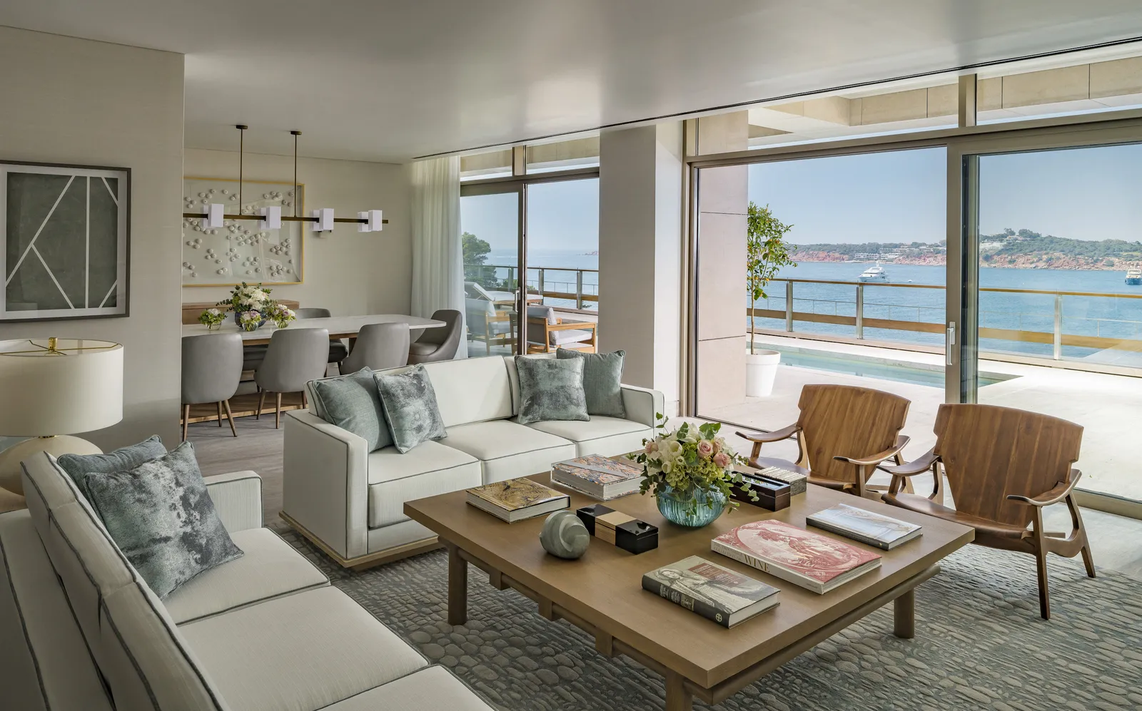 The living room of the Arion Royal Suite, with sofas around a low table, the dining table and glass doors to the terrace and its pool.
