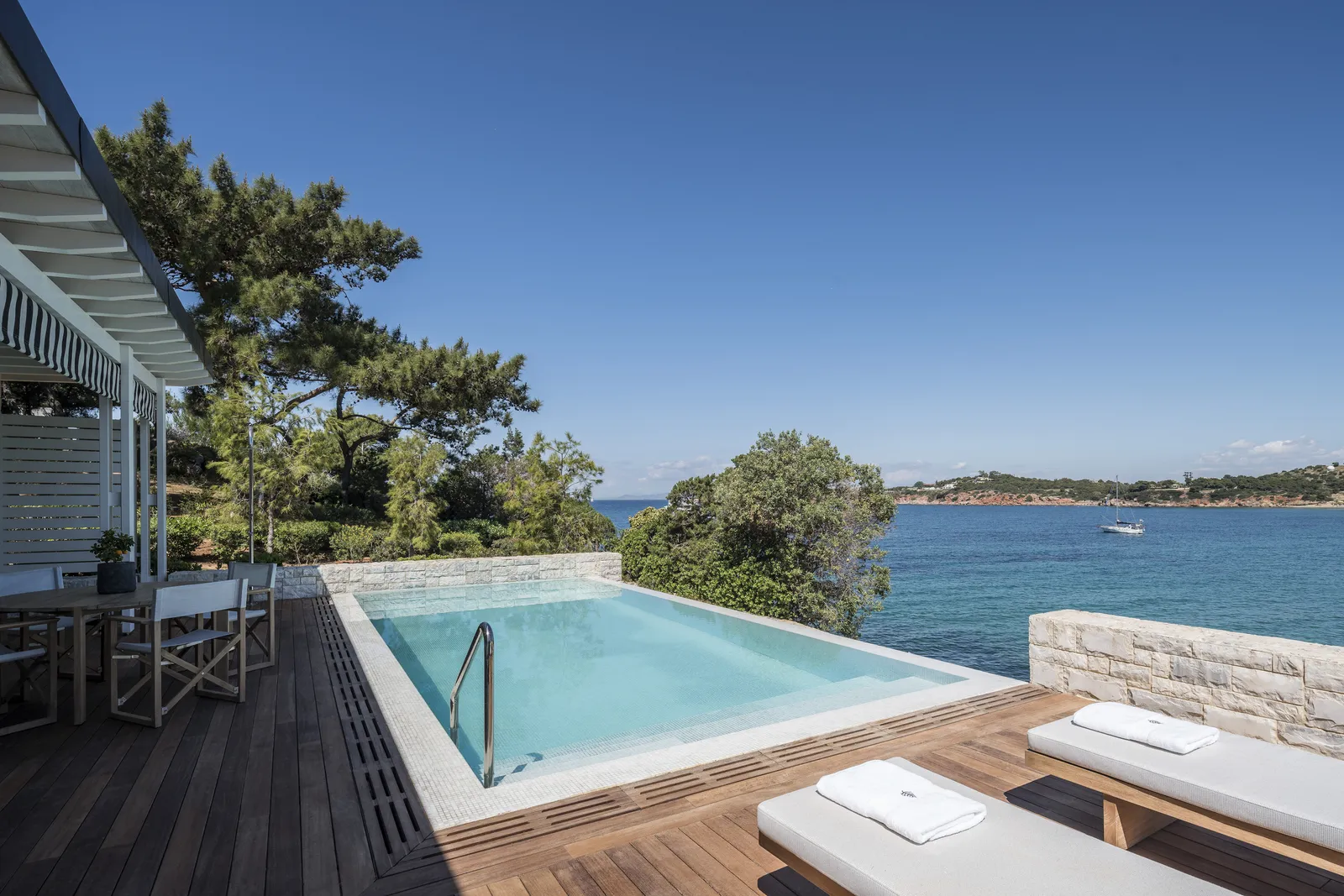 The infinity pool of a sea-view Bungalow Suite, on its timber deck, with the bay and the coast opposite.