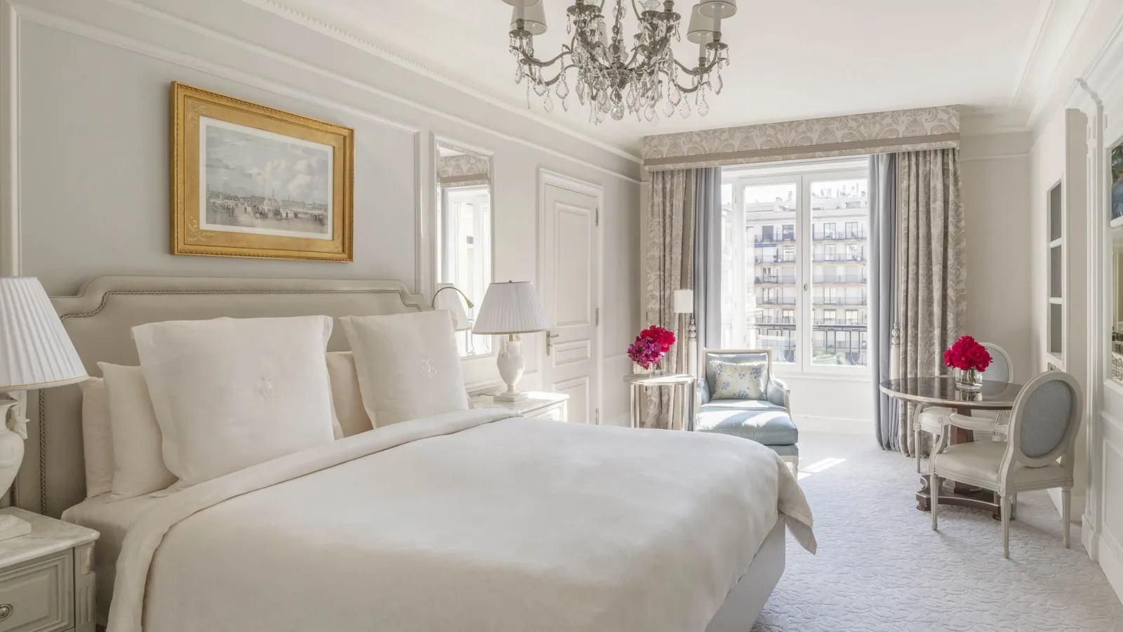 A pale bedroom with 2 armchairs and French windows