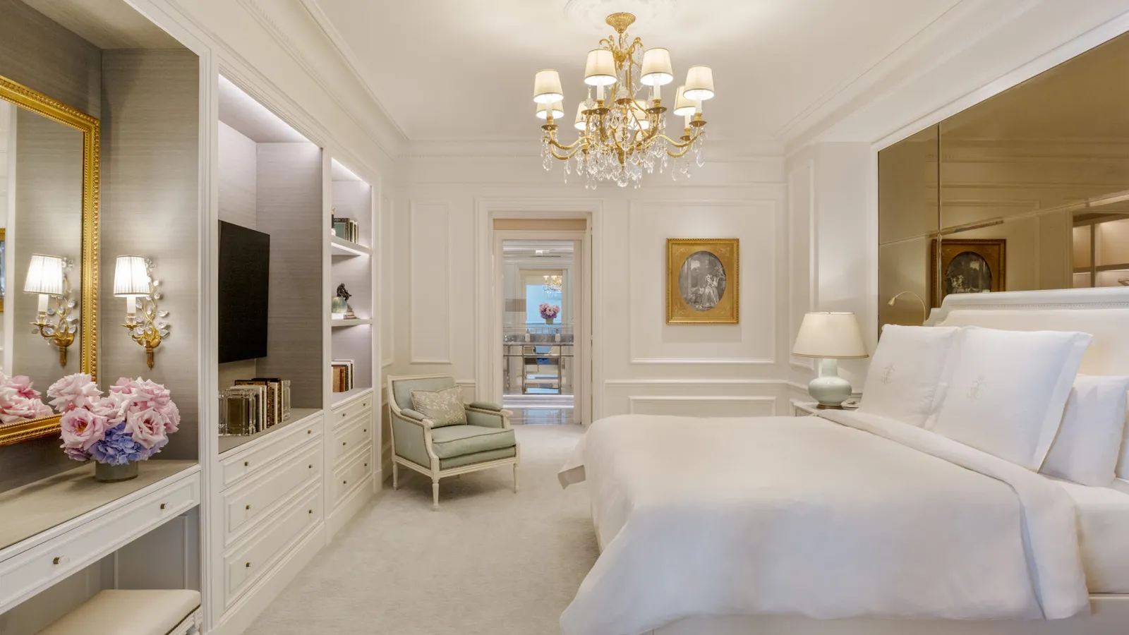 A spacious bedroom with a bed, chandelier and armchairs