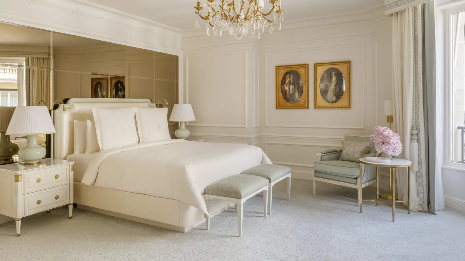 A bedroom with a bed, bench and wall mirror