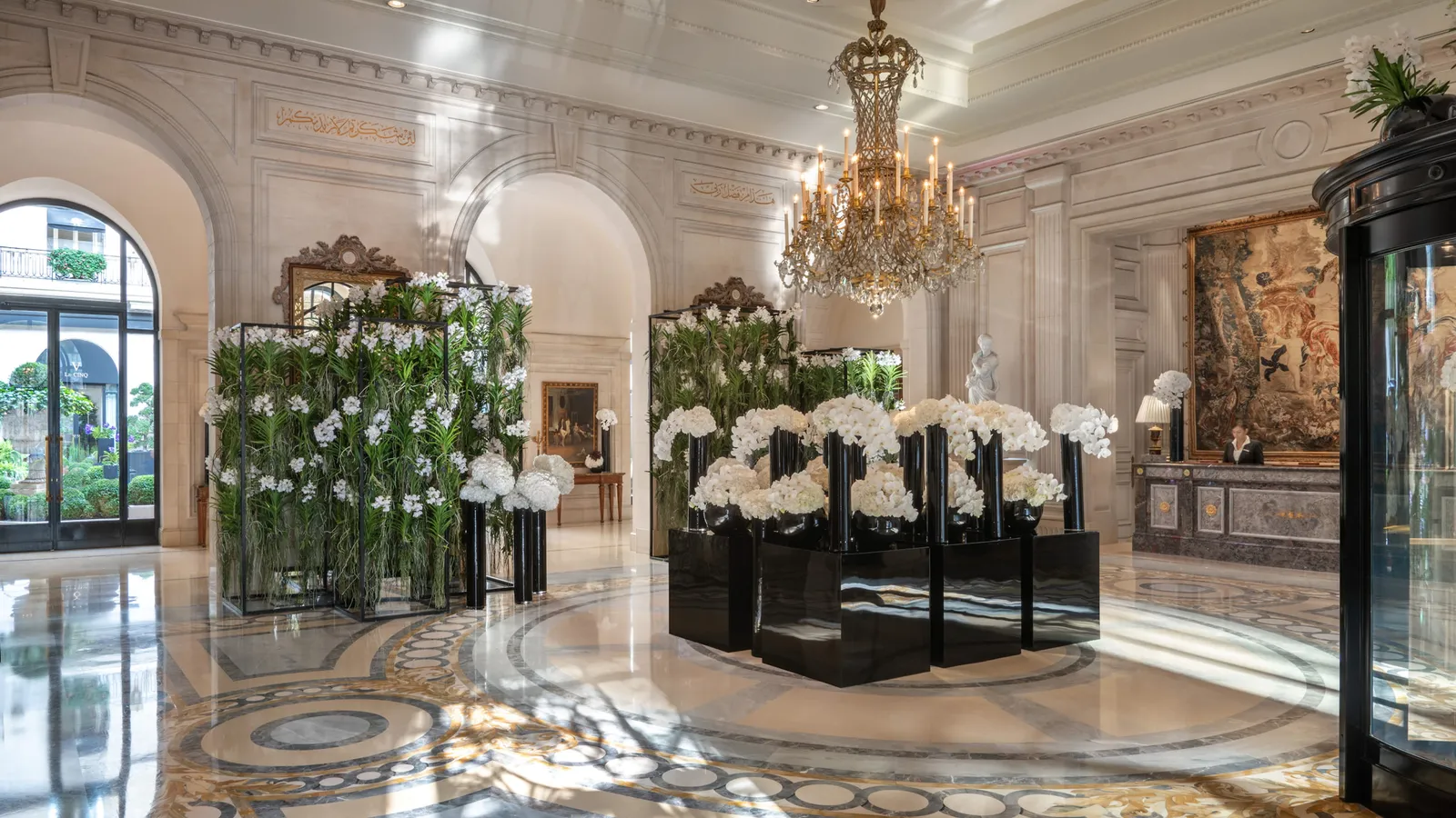 The lobby with floral arrangements, a chandelier and marble floor