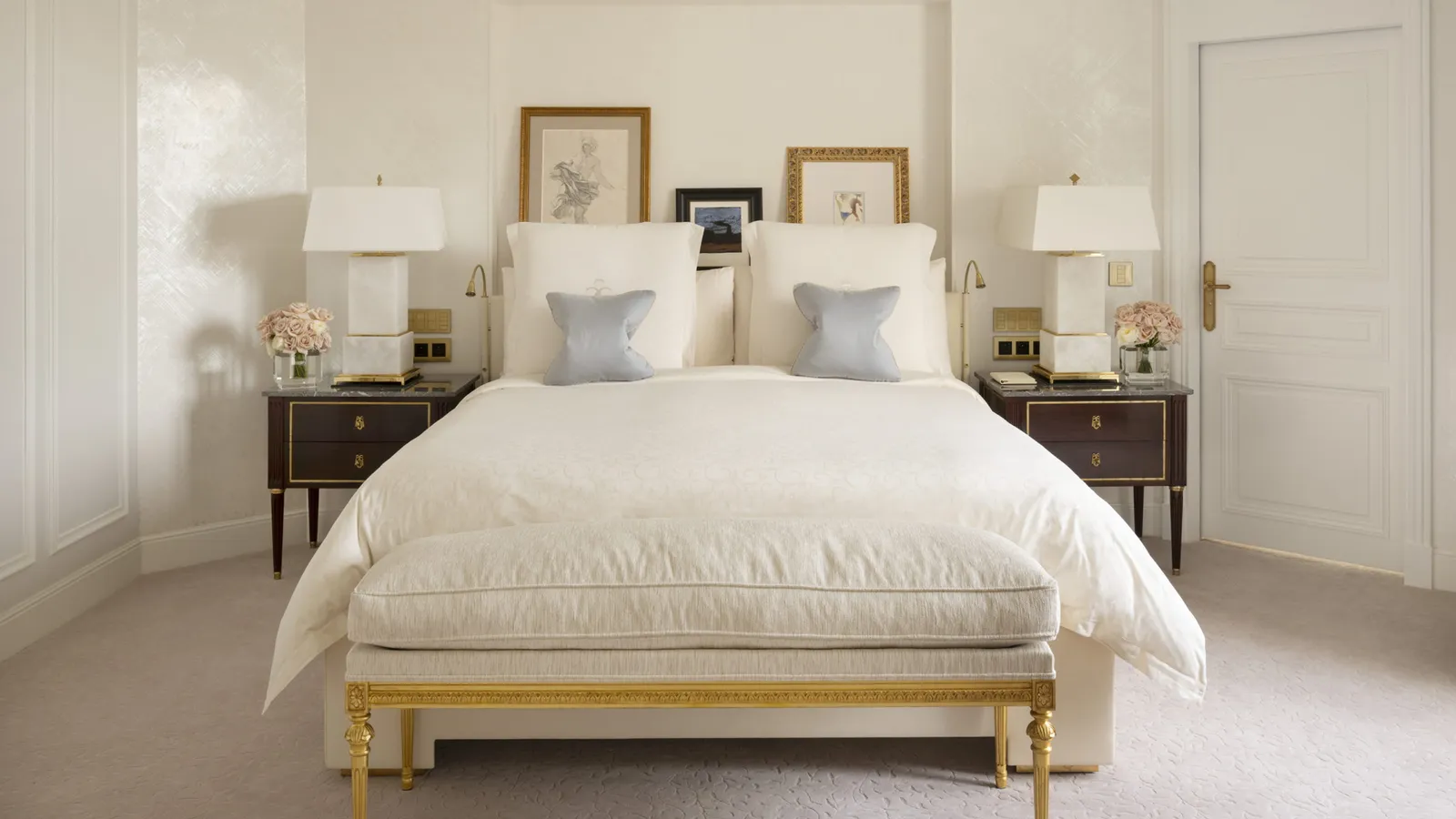 A white bedroom with a bed and dark bedside tables