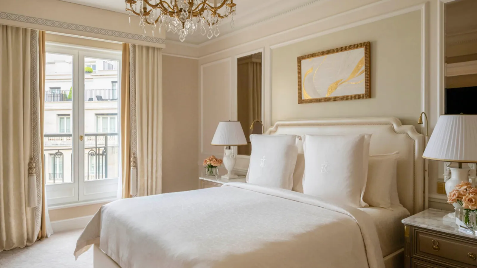 A pale bedroom with a bed, chandelier and French windows