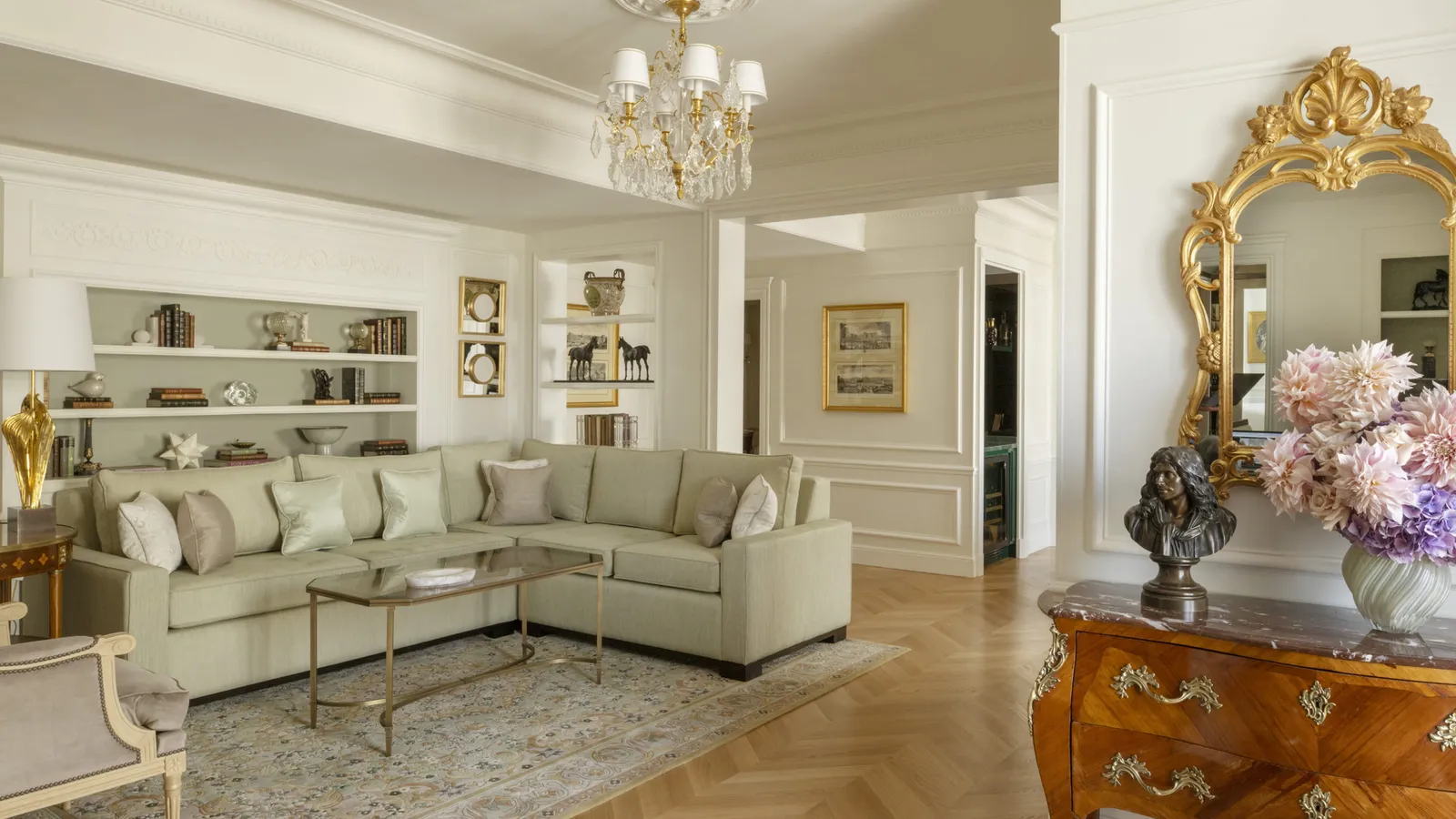 A sitting room with a pale sofa, gilded mirror and flowers